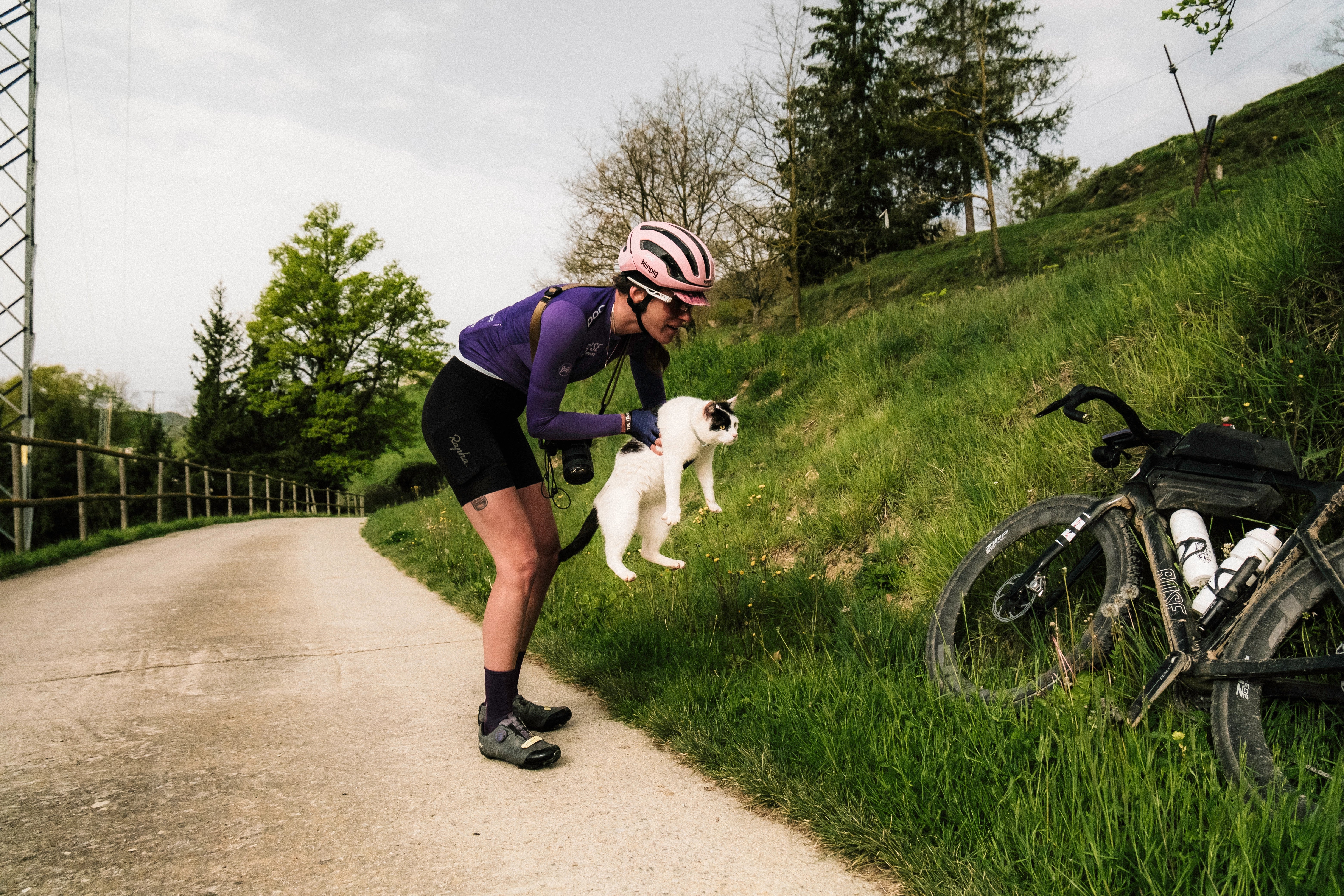 casco rosa ciclista con gato en el monte bici negra con portabotellas camino de ciclista sendero verde