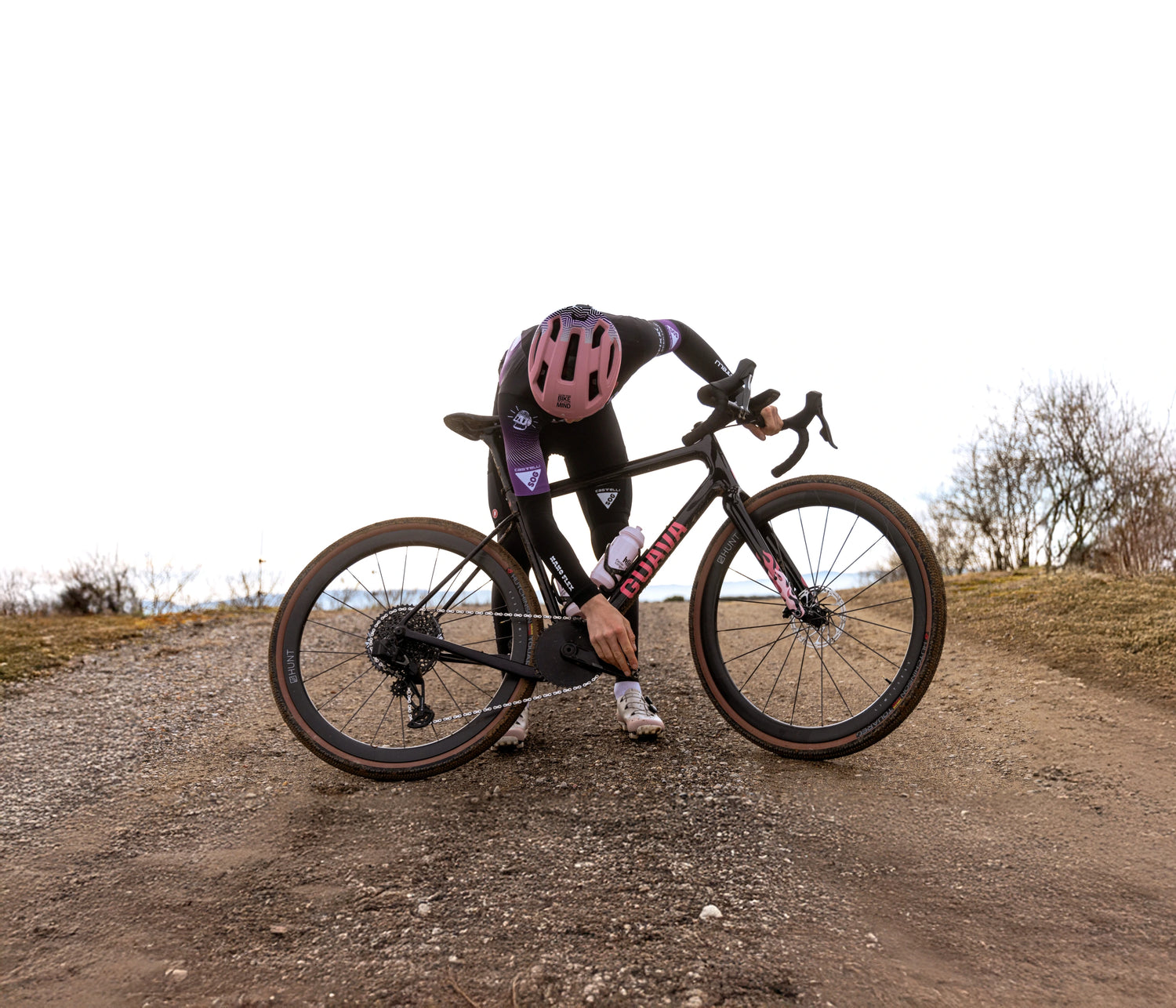 Ciclista sosteniedo la bici en una pista de tierra, con bicicleta de gravel