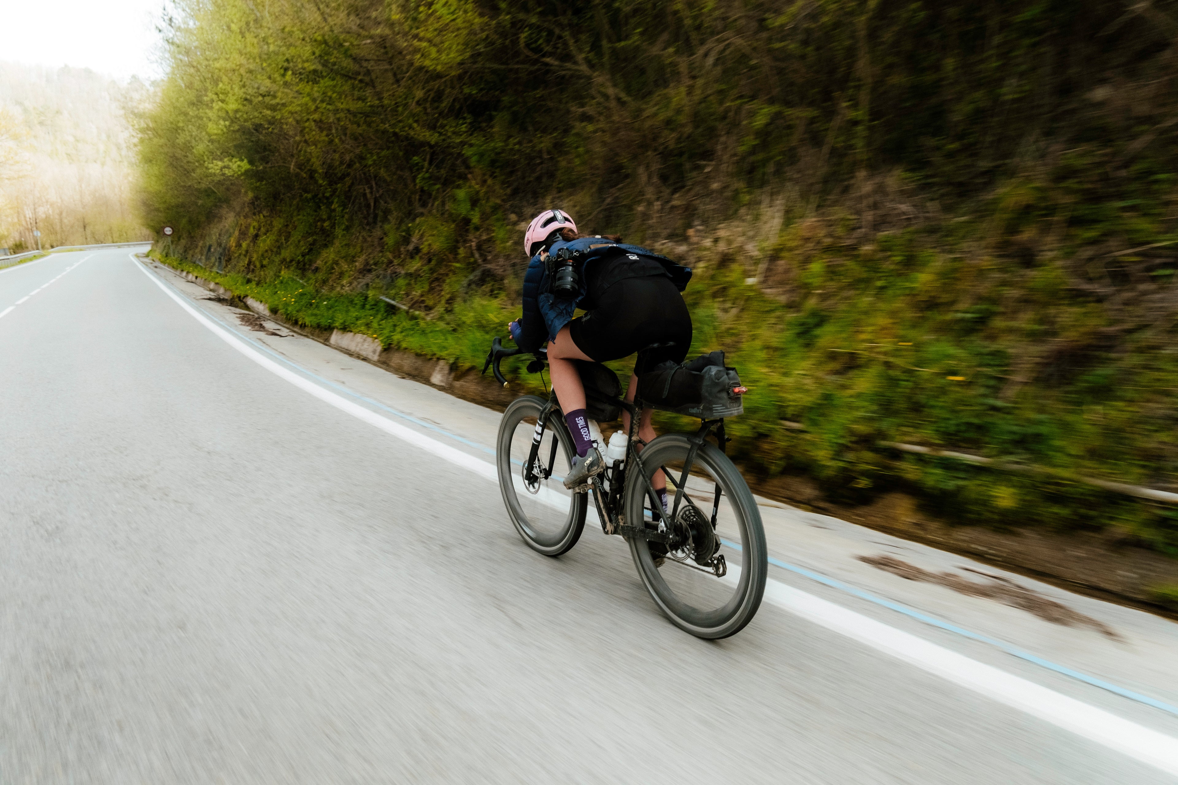 casco rosa ciclista bajando rápidamente una cuesta ciclista en unas curvas ciclista en una cuesta descendente rapidez