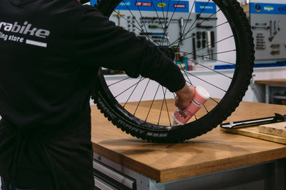 fondo de taller de bici rueda de bicicleta persona reparando rueda envase blanco roseando liquidoa ntipinchazos