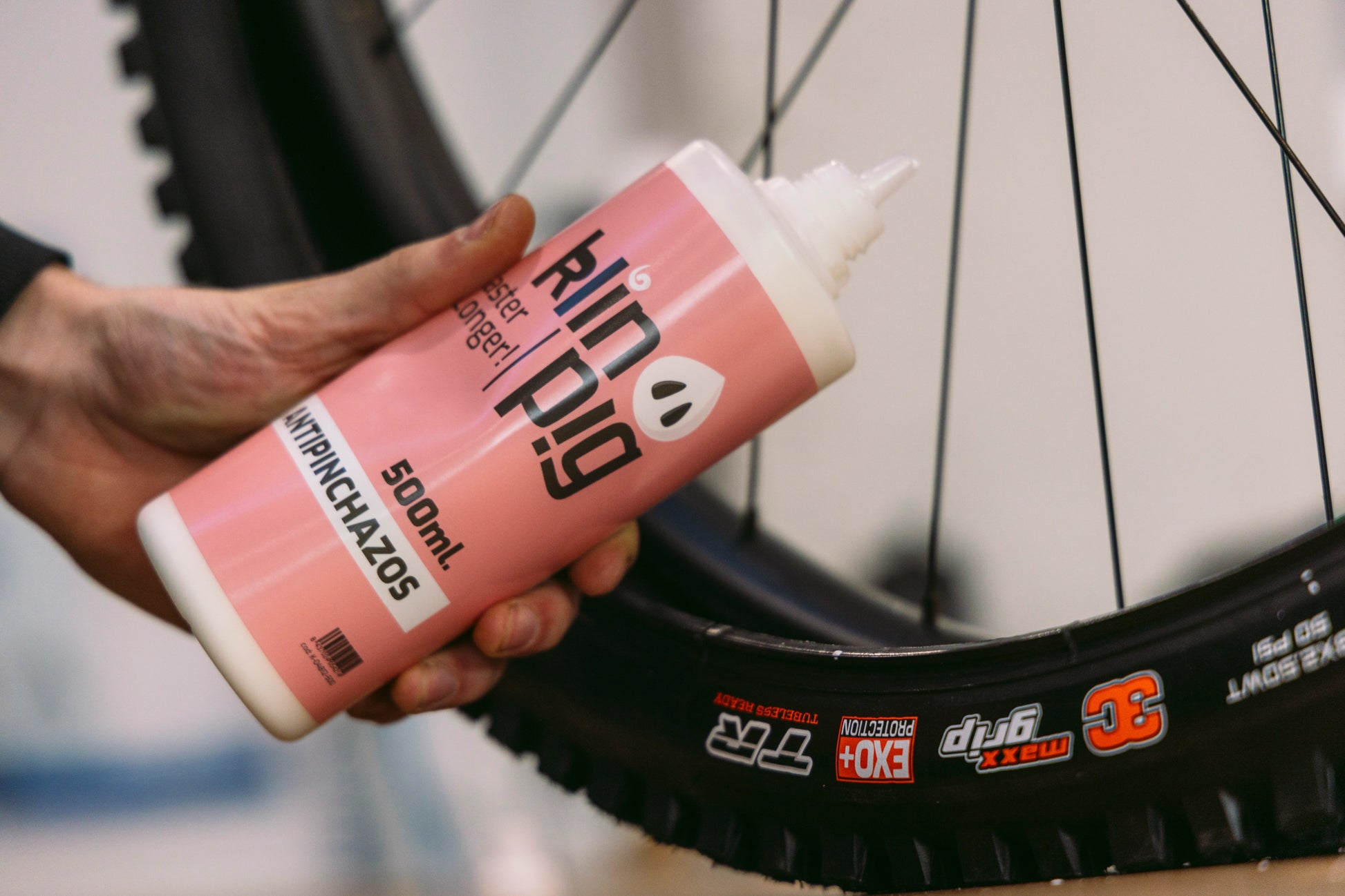 envase blanco con etiqueta rosa y negra rueda de bici radios de bi desenfoque gausiano del fondo de la imagen